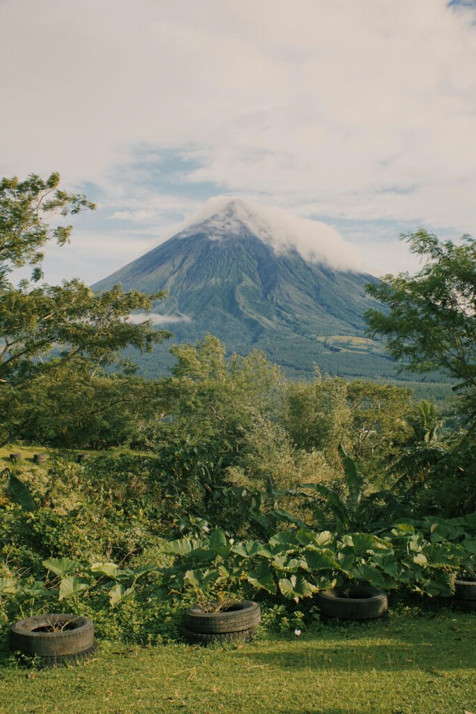 Scenic view of a volcano with lush vegetation in the foreground under a cloudy sky.